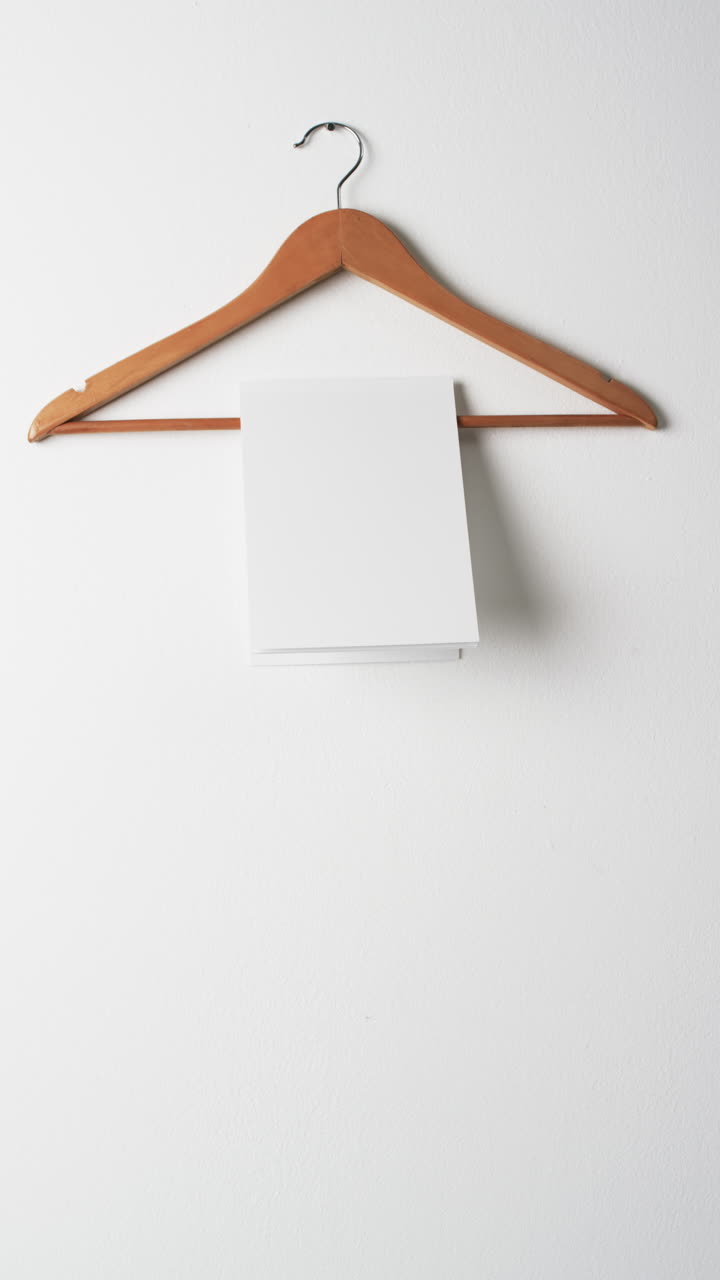Vertical video of book on hanger with white blank pages and copy space on white background
