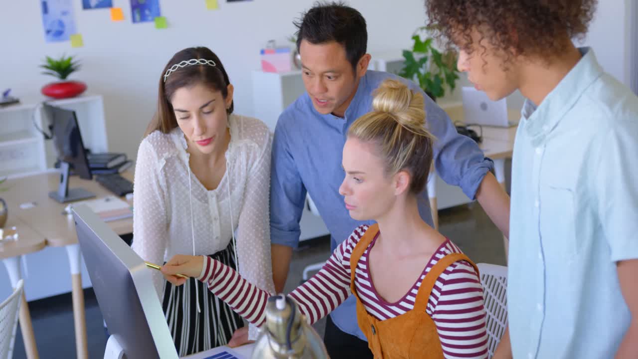 Vista lateral de jovens profissionais multirraciais trabalhando em computador de mesa na mesa em escritório moderno 4K