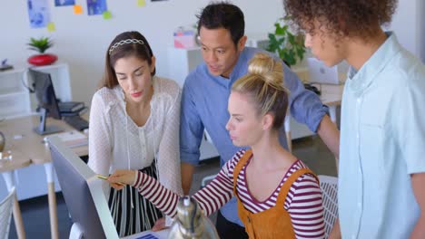 Side-view-of-young-mixed-race-business-people-working-on-desktop-pc-at-desk-in-modern-office-4k