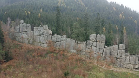 aerial shot of people hiking a mountain trail alongside a rock wall, breathtaking destination