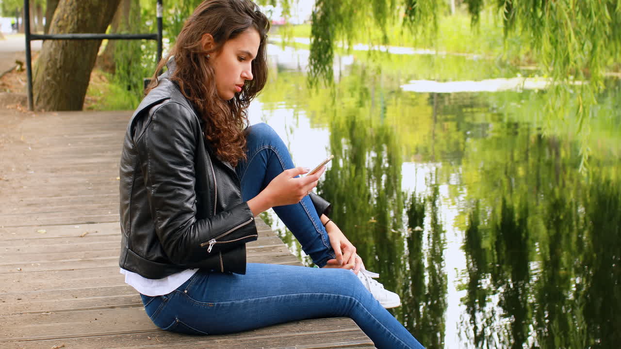 Woman using mobile phone near river 4k