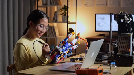 teen asian girl repairing a cyborg hand at home