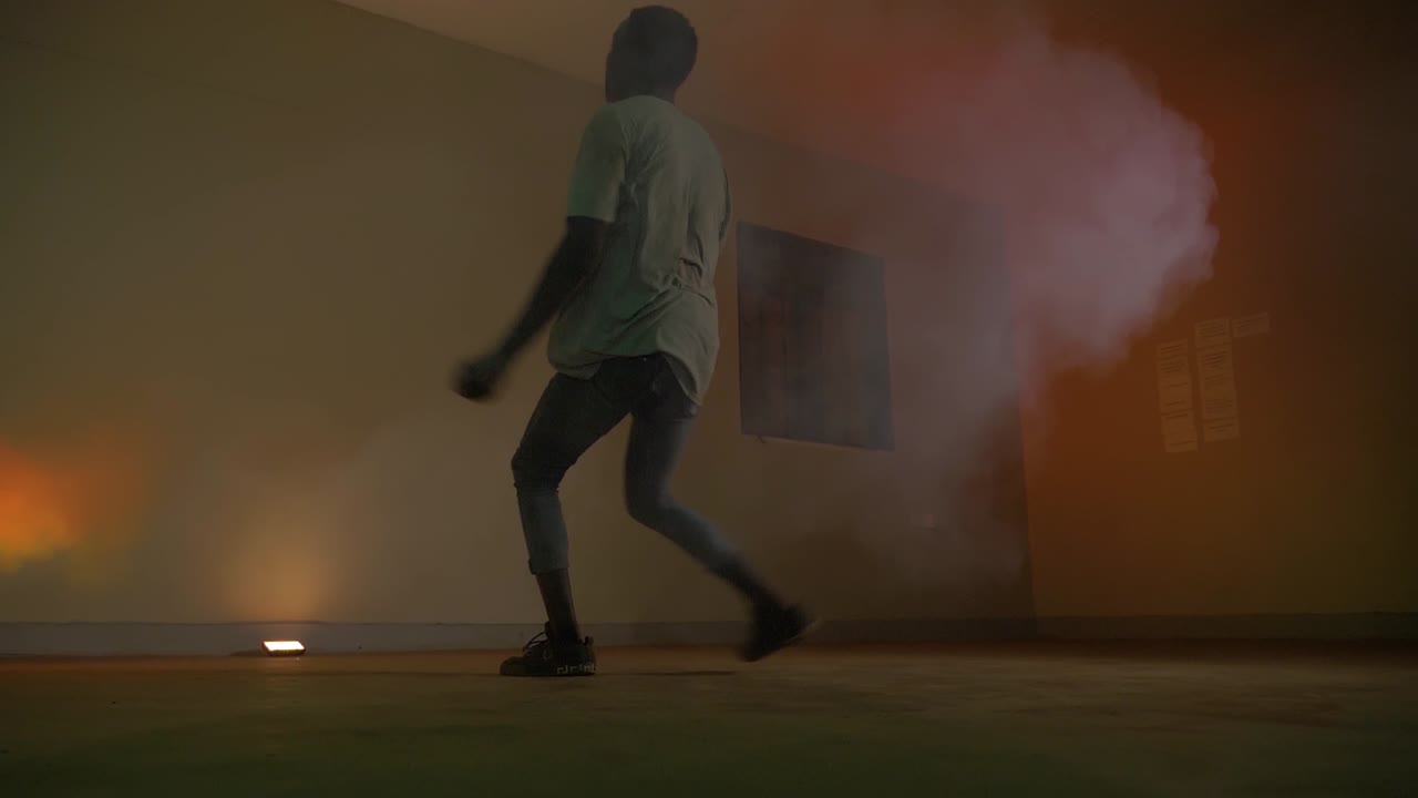 toma en cámara lenta de la juventud africana haciendo una voltereta corriendo y girando en luces disco y humo de color naranja