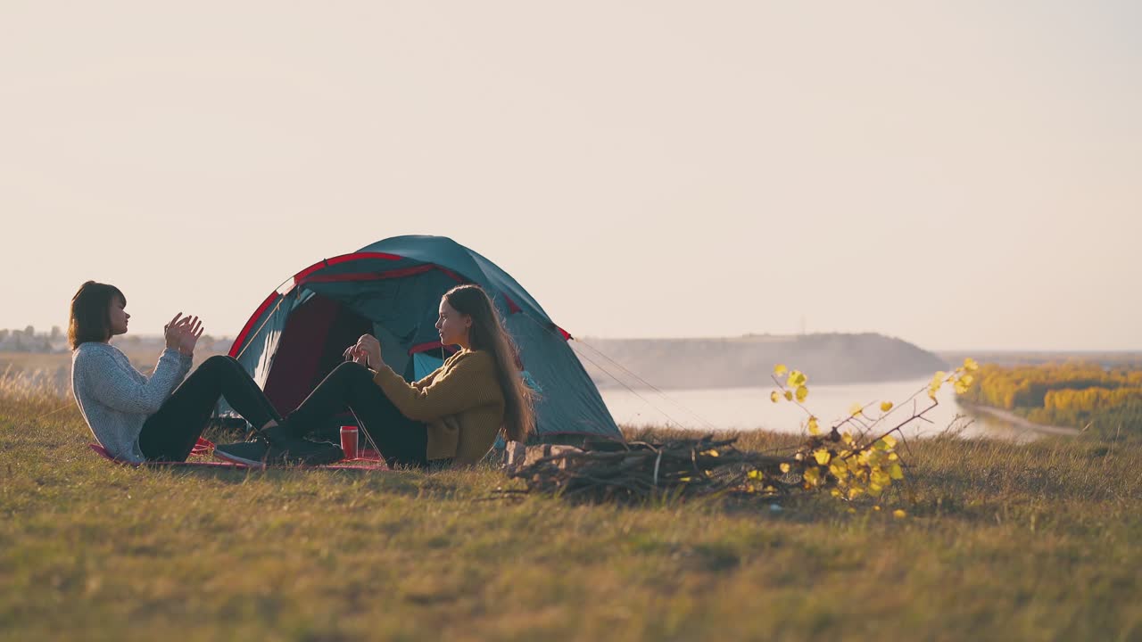 여자 관광객 들 은 텐트 에 따라 캠프 에서 손 을 박자 로 복부 운동 을 한다