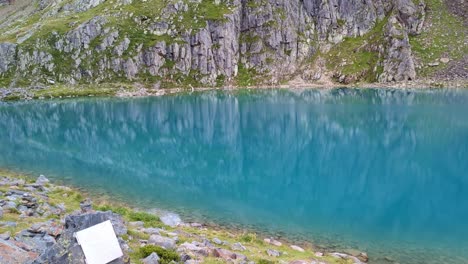 pan sobre el lago alpino remoto de color turquesa el enorme glaciar en el fondo