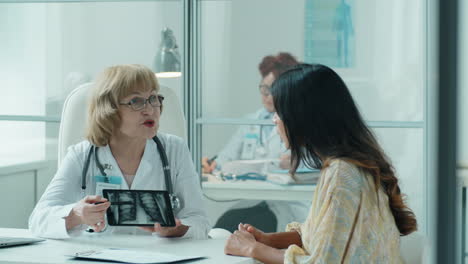 senior female doctor explaining chest x-ray on tablet to woman