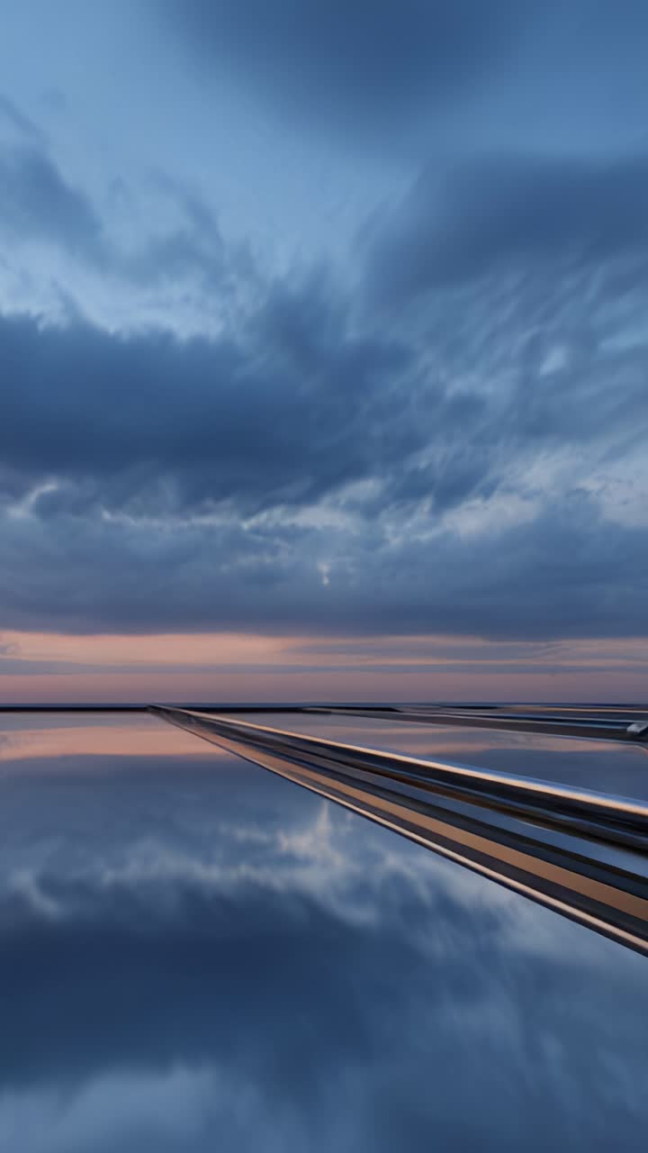 A solitary figure in a suit walks along a reflective, serene surface as the sun sets below the horizon, casting a beautiful blend of colors in the sky