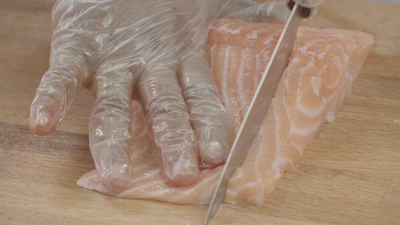 스시 바에서 스시 셰프가 신선한 연어를 슬라이스합니다.