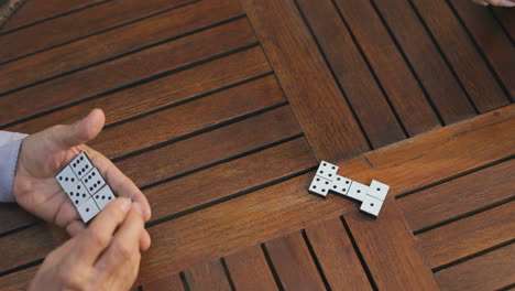 Close-Up-Of-The-Two-Old-Friends-Starting-Playing-Domino-Game-On-The-Wooden-Table-And-Doing-Their-Turns