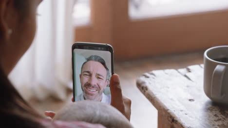 young mother and baby having video chat with father using smartphone waving at little daughter enjoying family connection