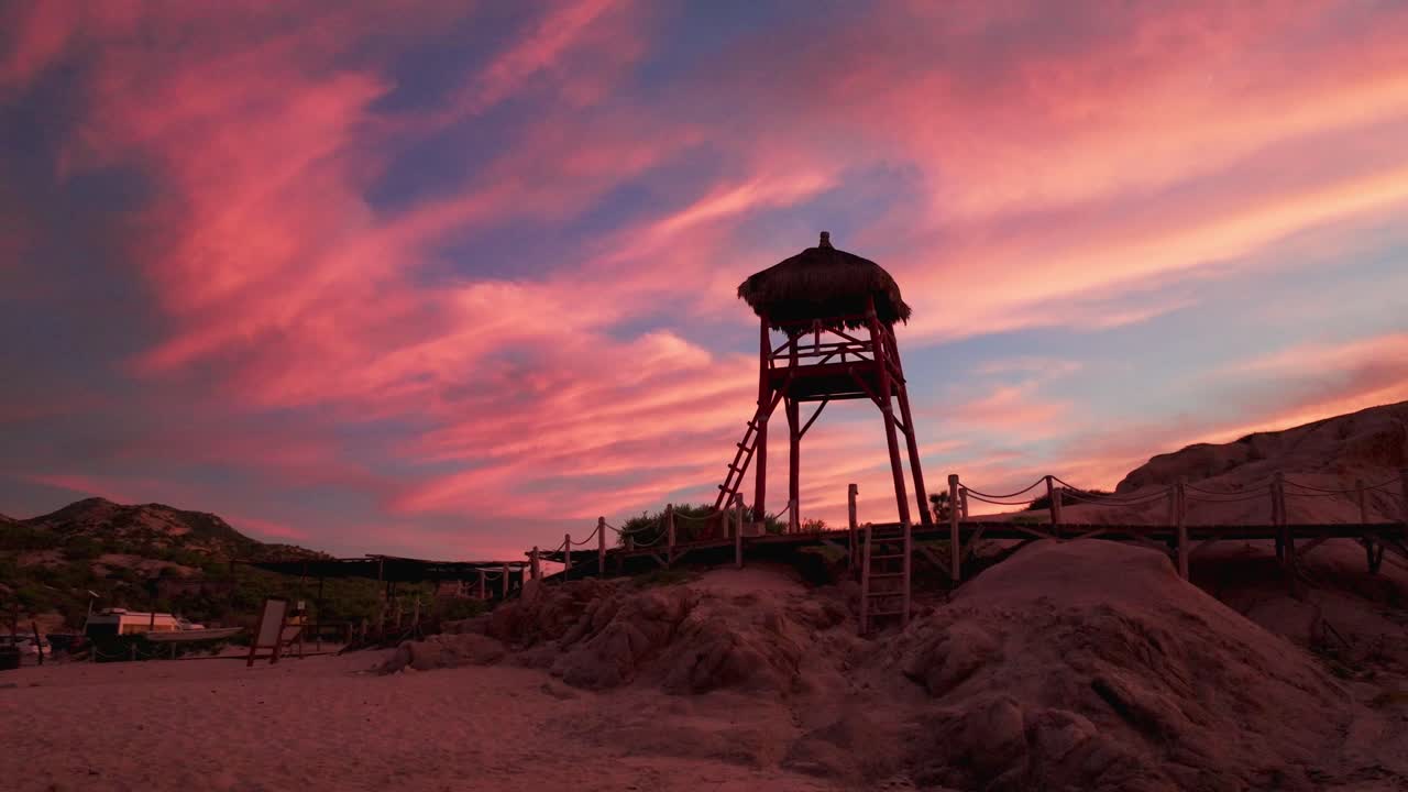 silhueta de salvavidas de madera contra las nubes del atardecer de fuego esponjoso rosa