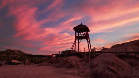 wooden lifeguard stand silhouette against pink fluffy fire sunset clouds