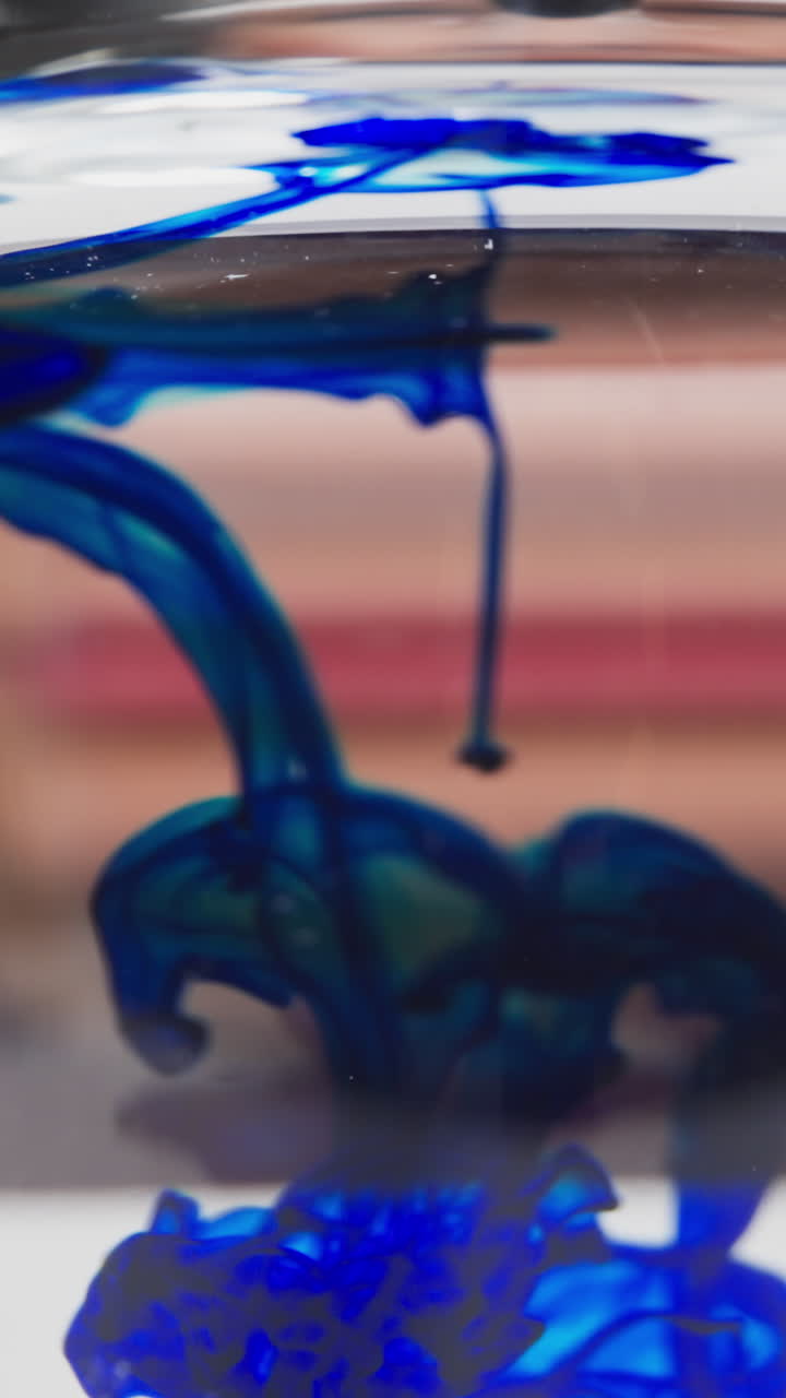 Dark blue reagent flow diffuses in transparent liquid under chemist control slow motion. Probe lens footage of lady glass-distorted face macro view