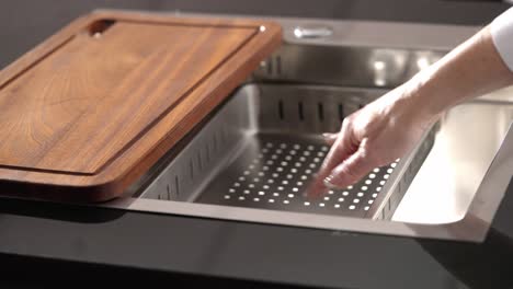 Kitchen-worktop-with-wood-cut-out-and-metal-tap-in-steel-kitchen