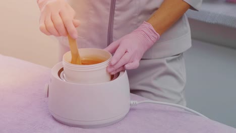 azúcar líquido para la depilación de la piel. toma de primer plano. depilación y concepto de belleza - pasta de azúcar o miel de cera para la eliminación de cabello con palos de espátula de cera de madera