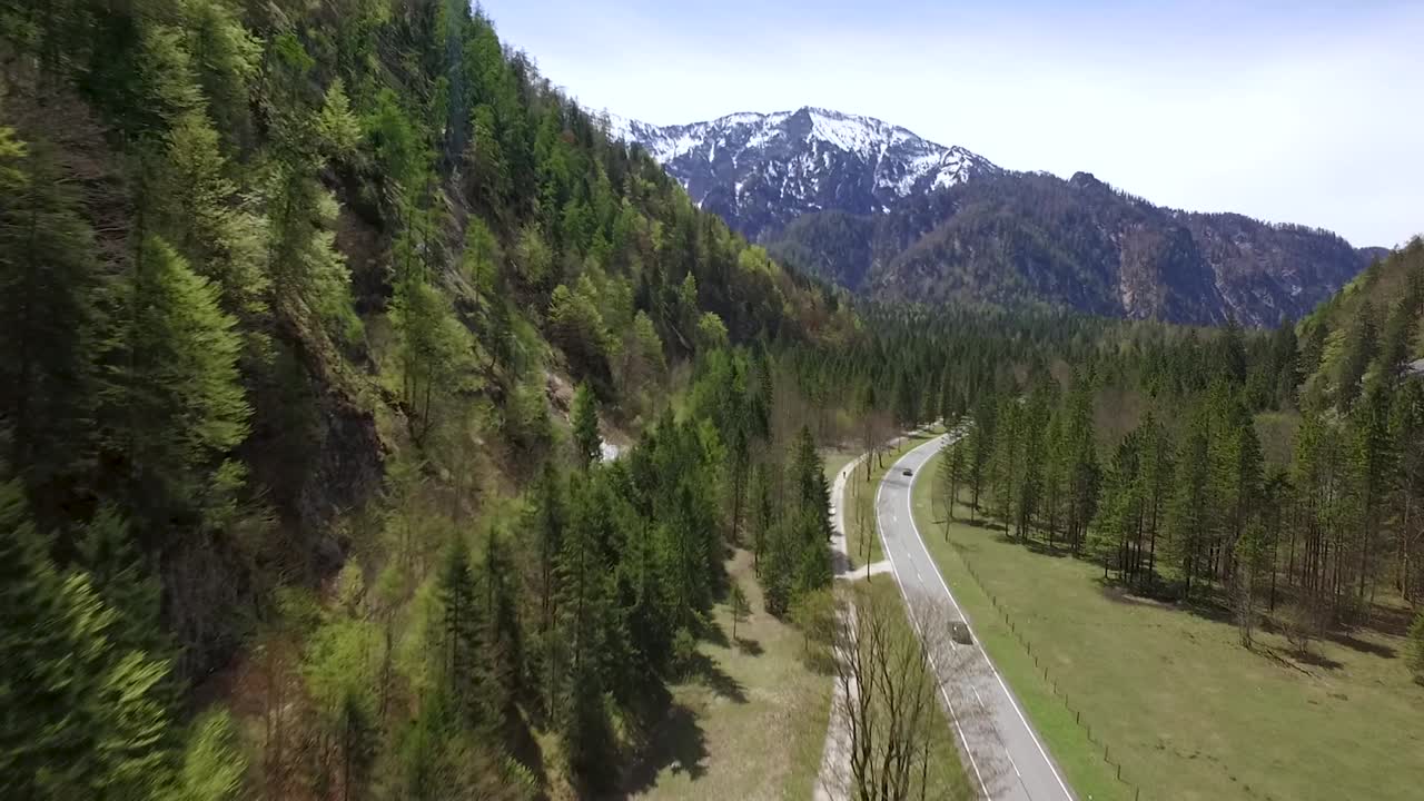 un disparo de drone de coches conduciendo en una carretera por los alpes