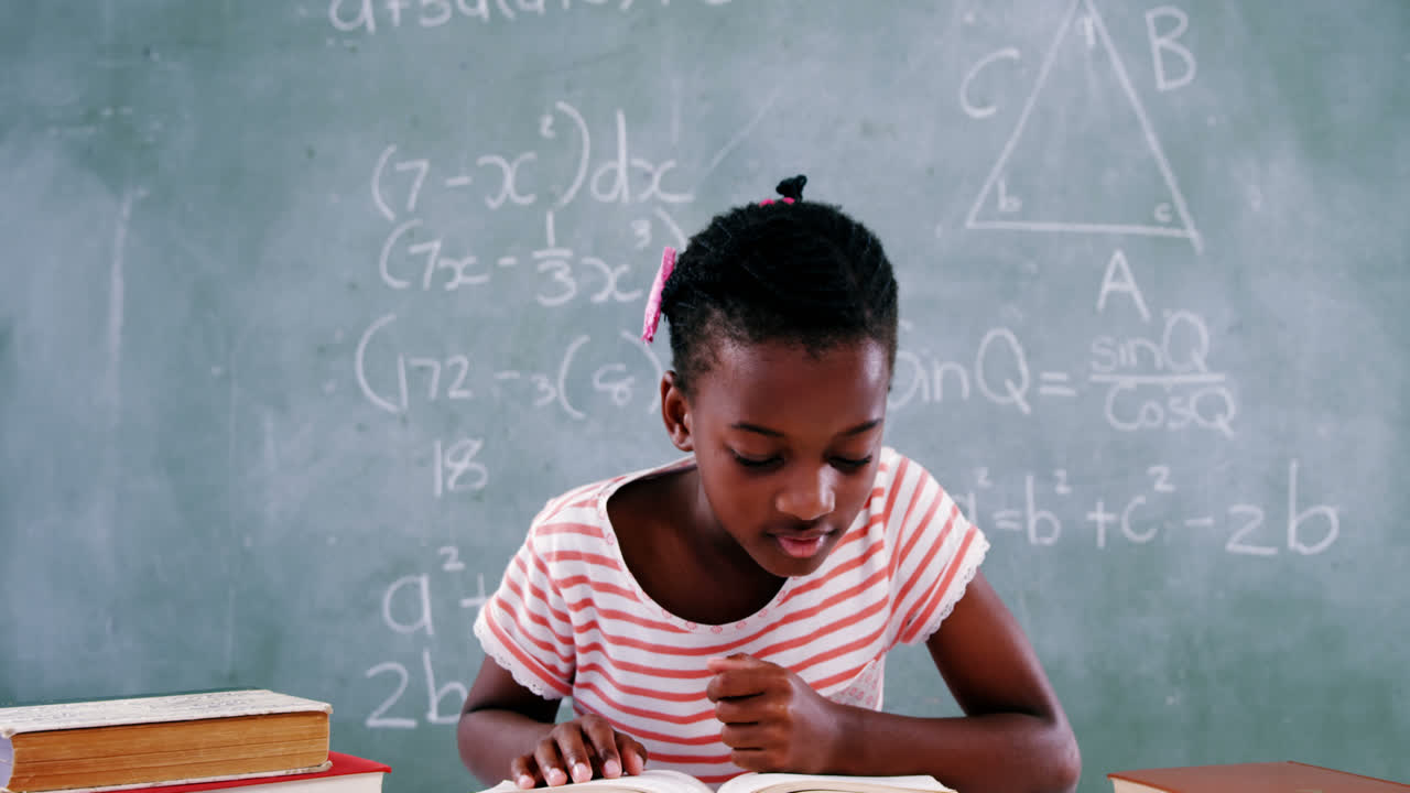 Schoolgirl reading book in classroom