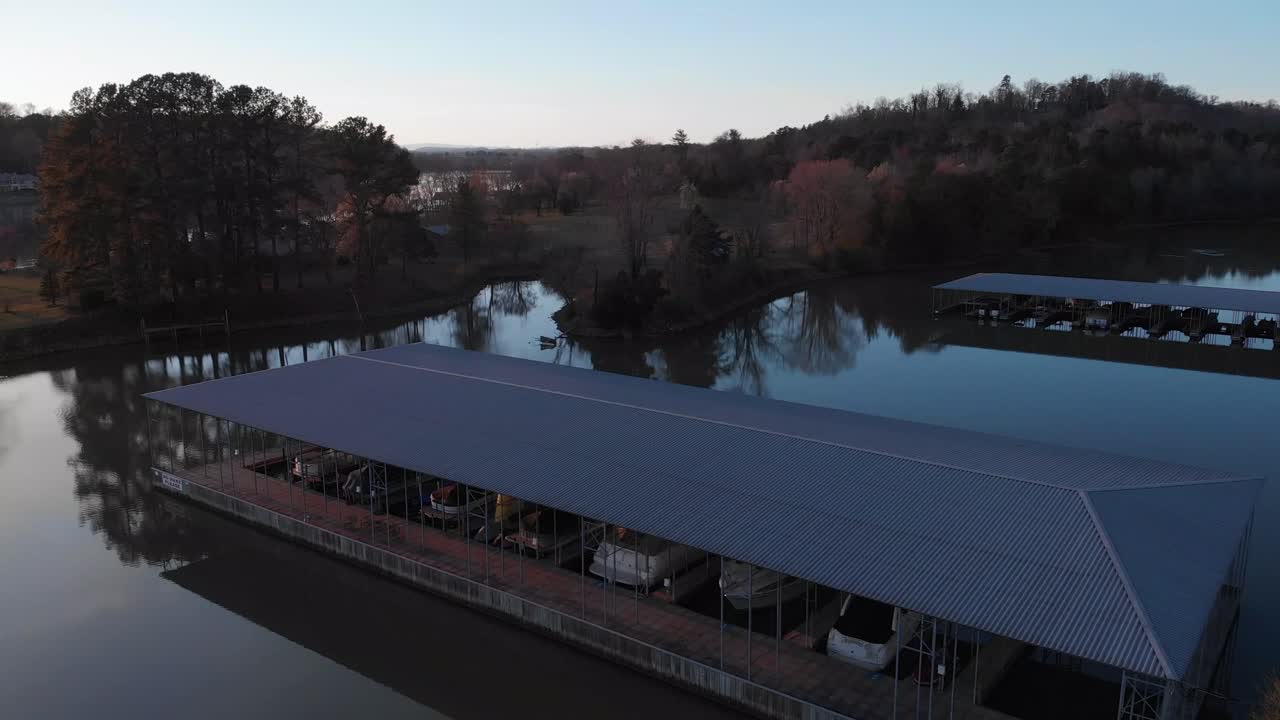 잔잔한 물과 그 뒤에 있는 육지가 있는 보트 부두 위로 천천히 떠오르는 드론 영상