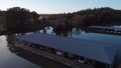 drone footage slowly rising above the boat docks with calm water and land behind it