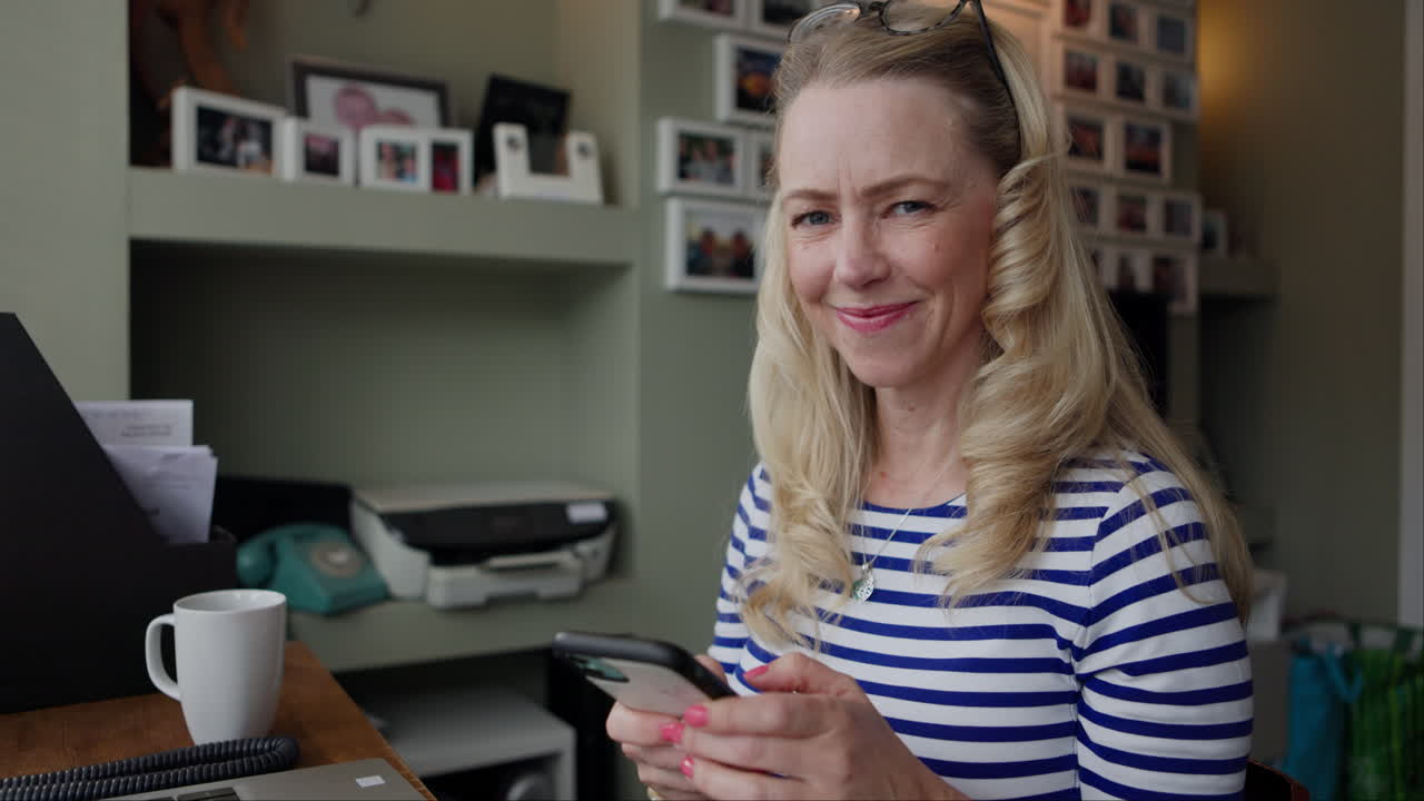Woman using smartphone in home office