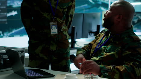 un experto del ejército enojado en un puesto de mando de la base de energía monitorea imágenes de satélite