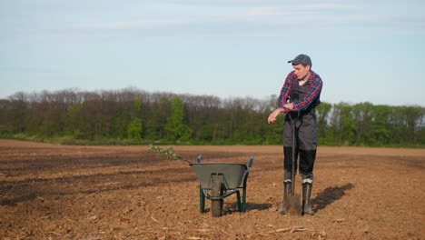 farmer resting near a wheelbarrow in a field