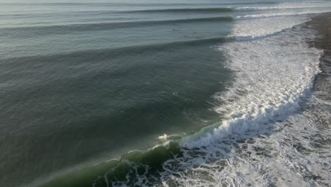 Vista-Aérea-De-Sudáfrica-Jeffrey&#39;s-Bay-Los-Surfistas-Montan-Largas-Olas-En-El-Punto-De-Surf