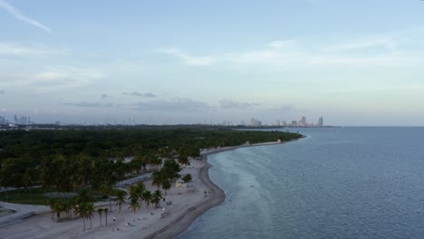 Toma-Aérea-Con-Drones-De-La-Hermosa-Playa-Tropical-Rodeada-De-Palmeras-En-El-Parque-Crandon-En-Key-Biscayne-En-Las-Afueras-De-Miami,-Florida,-En-Una-Cálida-Y-Soleada-Tarde-De-Verano.