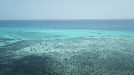 Panorámica-Aérea-De-Drones-Alrededor-De-La-Gran-Barrera-De-Coral-Con-Barcos-En-El-Agua-Azul-Clara-Tropical