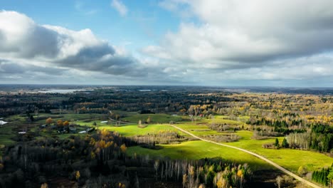 Drone hyperlapse over verdant countryside landscape in autumn covering vast area of land and forest. Small village from above in rural area. Tree leaves coloring.