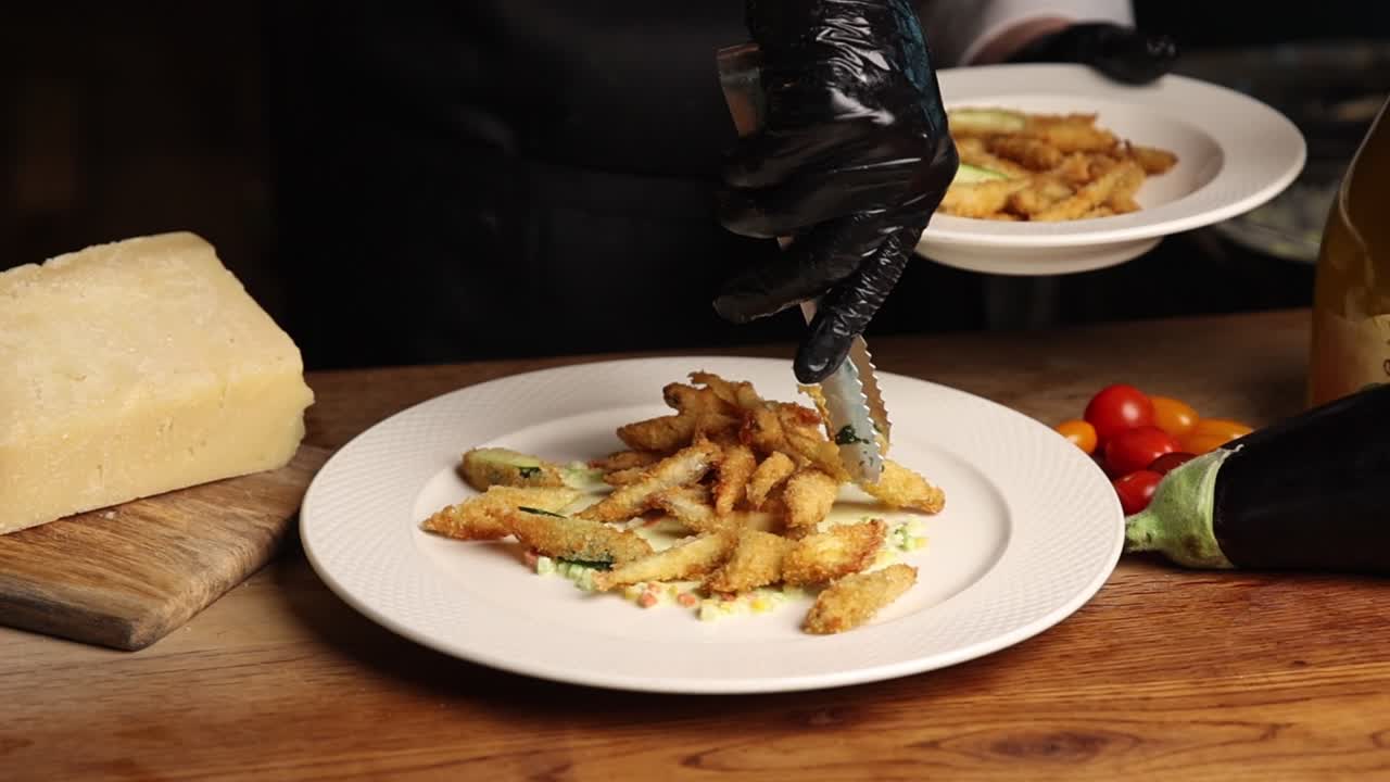 Chef Plating Fried Vegetables onto a White Dish in a Restaurant Kitchen