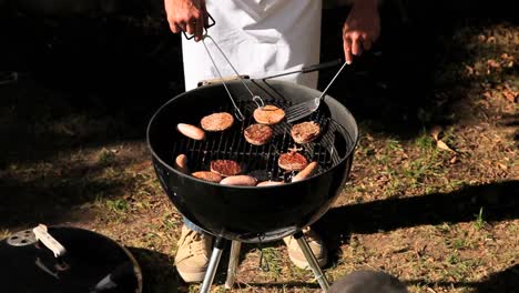 man cooking hamburgers on barbecue