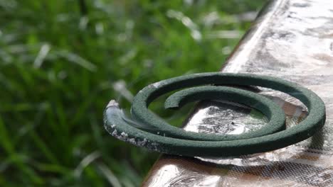 closeup of burning mosquito coil on table with green blurred background