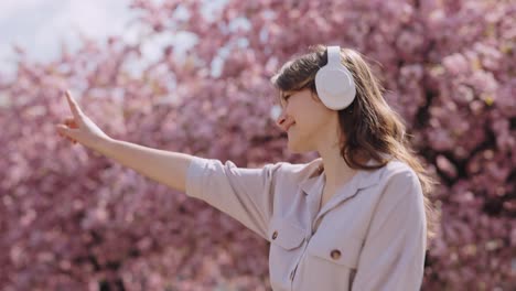woman enjoying music in a cherry blossom park