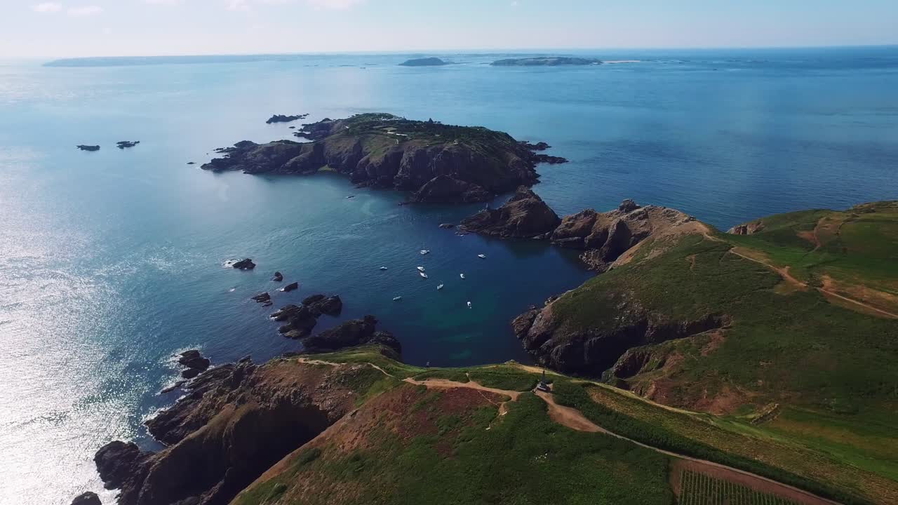 Aerial drone view of the rocky coast and the Atlantic Ocean of the island of Sark where many sail boats are docked, Channel Islands