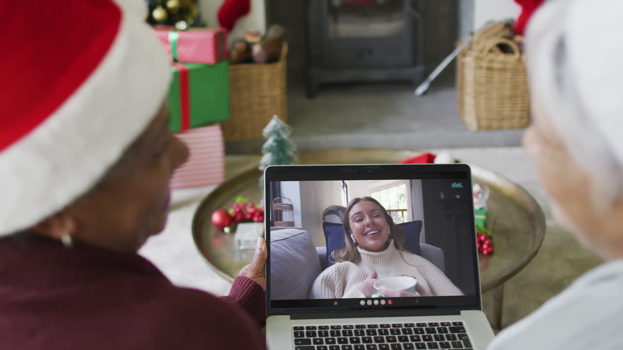 diversas amigas mayores que usan una computadora portátil para una videollamada de navidad con una mujer feliz en la pantalla