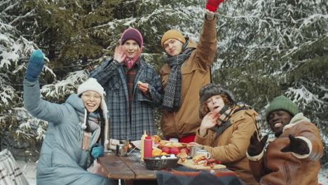 portrait of happy friends at camp table in winter forest