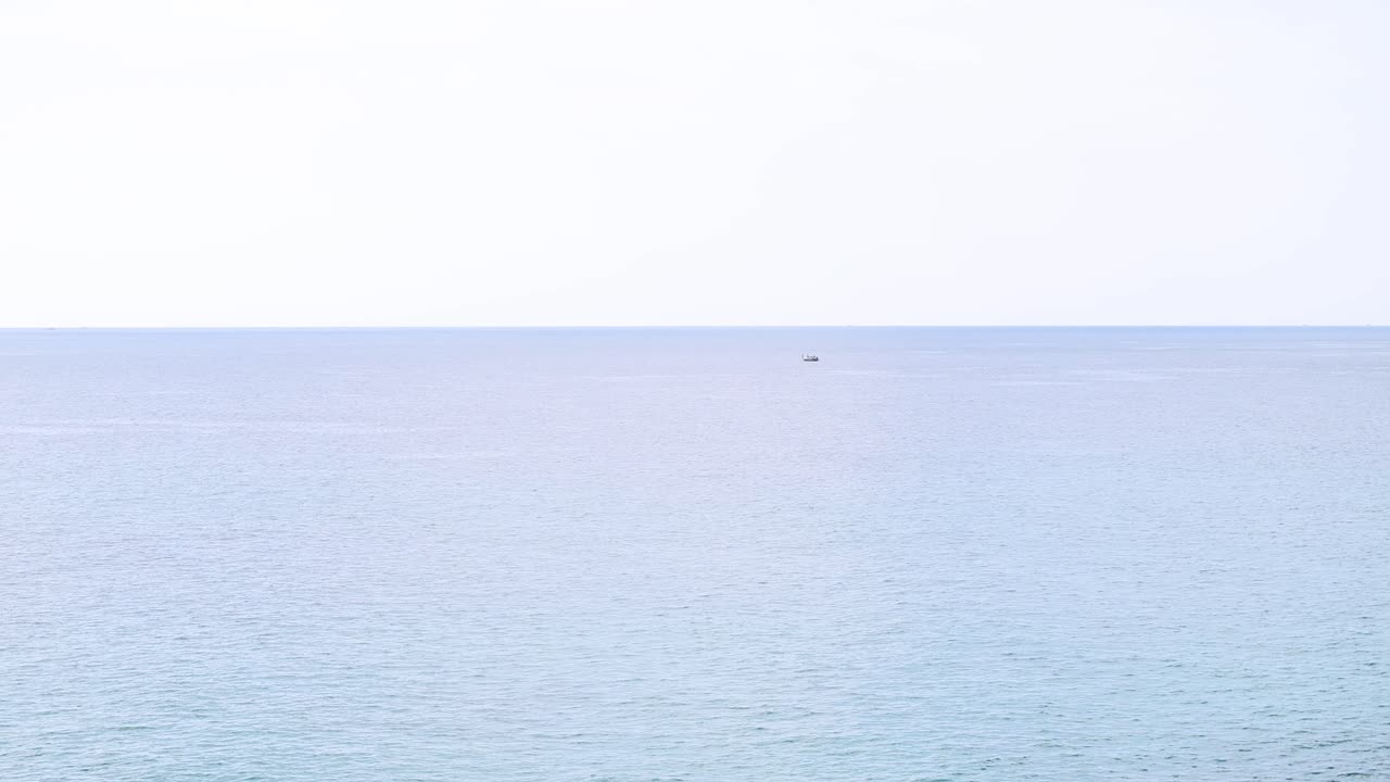 A tranquil ocean scene with calm waters and distant islands under soft daylight, captured in Phuket, Thailand