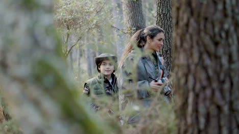 tracking shot of young kid and his mother with camera walking in the woods and exploring wildlife