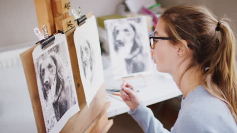 Weibliche-Teenager-Künstlerin-Sitzt-An-Der-Staffelei-Und-Zeichnet-Mit-Kohle-Ein-Bild-Eines-Hundes-Aus-Einem-Foto