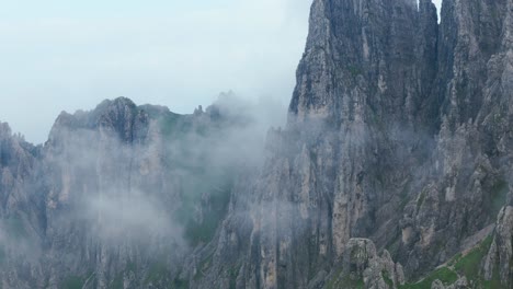 lombardy, italy - an awe-inspiring view of jagged peaks veiled in fog, emerging from the rugged slopes of grignetta - aerial drone shot