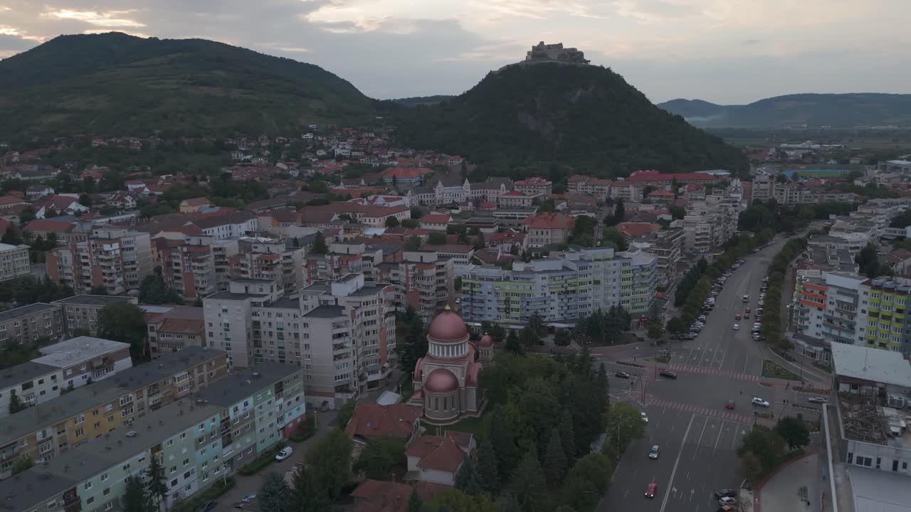 Vista panoramica al crepuscolo che mostra le cupole della chiesa, l’ambiente urbano e lo storico castello in cima alla collina