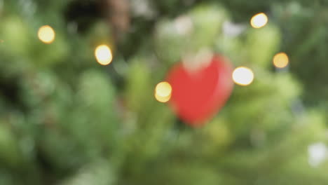 pull focus shot of heart shaped decoration hanging on christmas tree