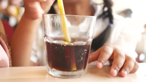 a young girl drinks from a glass of cola