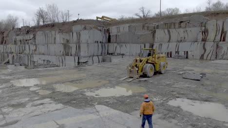 trabajador de la construcción camina hacia el camión cargador frontal en cantera de piedra