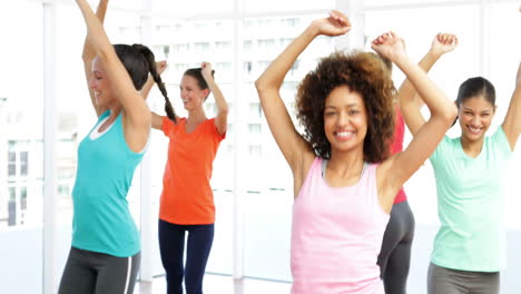 pretty instructor leading zumba class in fitness studio