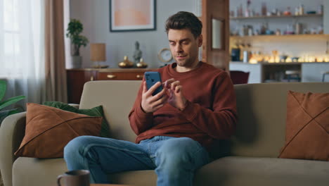 serious customer looking cellphone making online order at home. man swiping