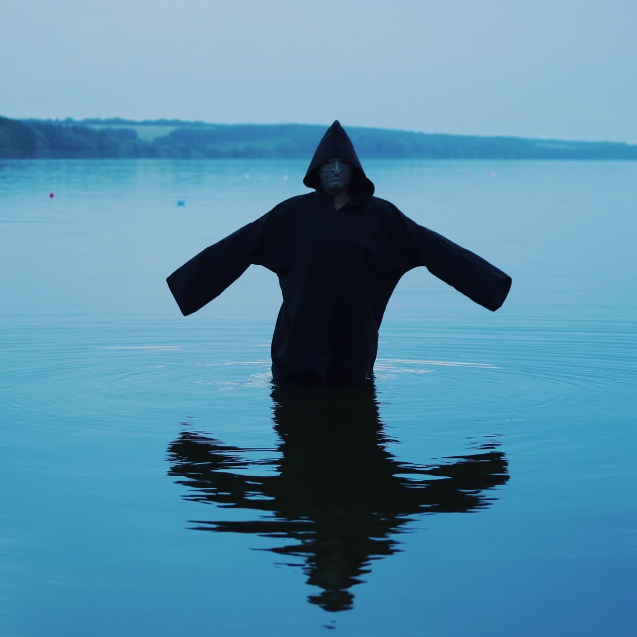 Terrible figure in a black robe in the water outdoor. Divination by Halloween