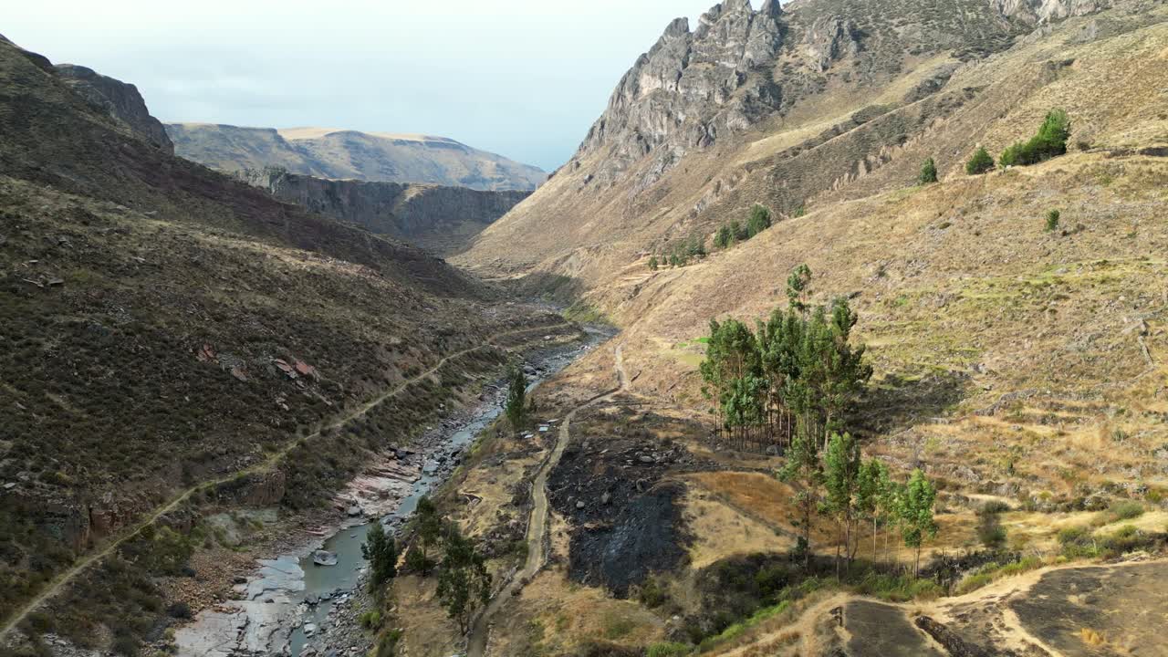 Drone footage capturing the first light of morning in a Peruvian valley, golden fields glowing beside a winding highland river
