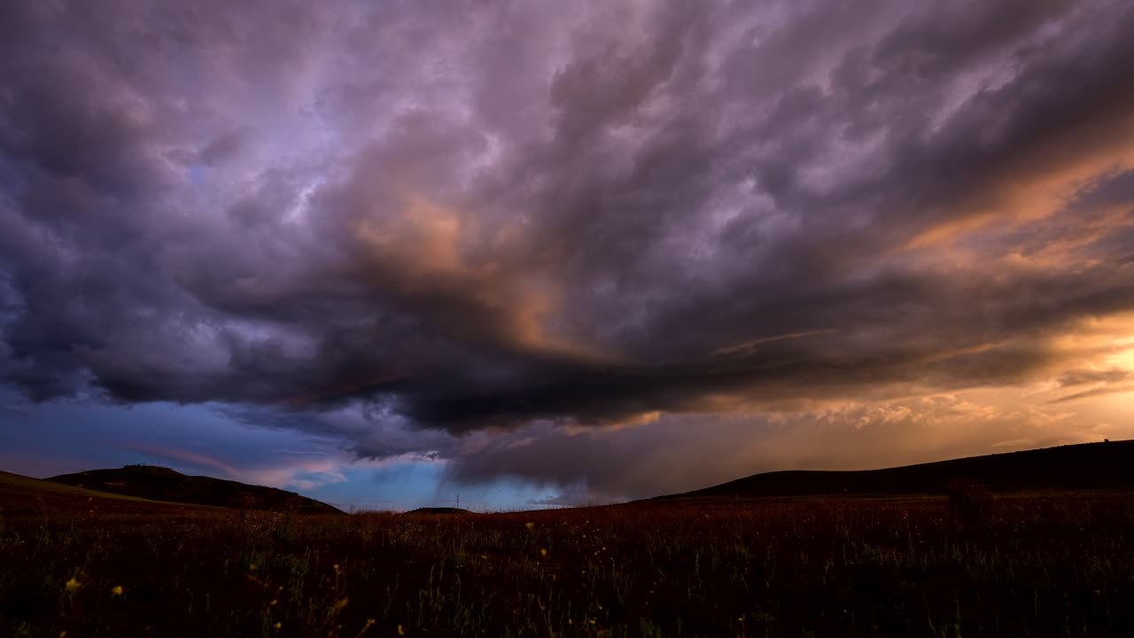 Timelapse storm clouds and sunset light over the Sacred Valley near Cusco, Peru, in the Andes, with dramatic sky colour shifting above rural hills and grassland